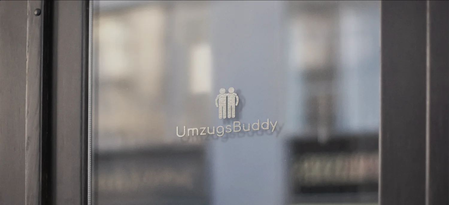 Das Logo von UmzugsBuddy mattiert auf einer Glastür, dahinter unscharf ein Büro